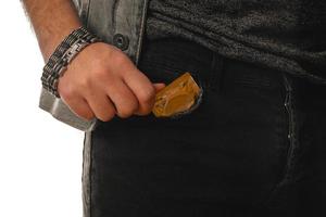 homem tira uma camisinha dourada do bolso foto