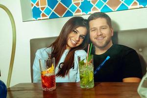 casal sorrindo para a câmera e fumando shisha foto