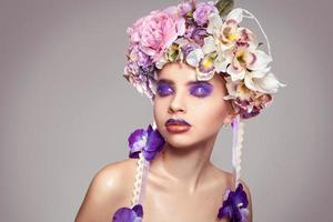 closeup de menina com coroa de flores na cabeça e maquiagem em tons de roxo foto