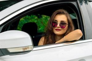 retrato de menina bonita moda em óculos de sol no carro foto