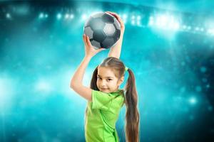 retrato de uma garotinha sorri para a câmera com uma bola de futebol nas mãos foto