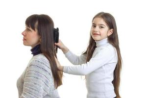linda garota penteando o cabelo e sua mãe sorrindo foto