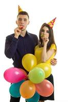 retrato vertical de alegre casal jovem soprando chifres em uma festa de aniversário foto