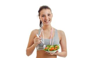 mulher de esportes feliz come uma salada e sorrindo na câmera foto