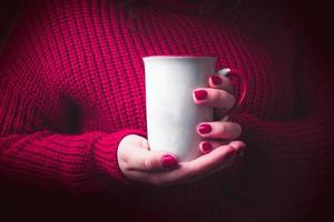 mulher com suéter vermelho aconchegante segurando caneca branca para maquete. foto