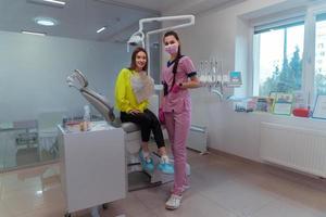 menina paciente feliz e dentista na clínica foto