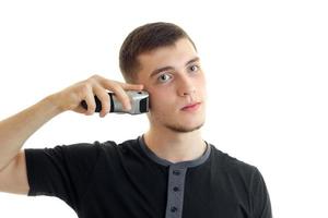 retrato de um jovem em uma camiseta preta que se barbeia com um rosto severo close-up foto