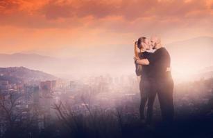 casal alegre em uma colina alta com vista para a cidade foto