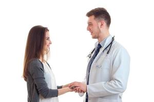 jovem linda garota com cabelo comprido fica em frente ao médico segura sua mão e eles estão sorrindo foto