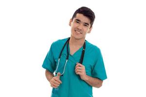 alegre jovem morena médico de uniforme azul com estetoscópio posando isolado no fundo branco foto