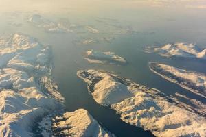 uma vista aérea das montanhas cobertas de neve dos fiordes da noruega no inverno. foto