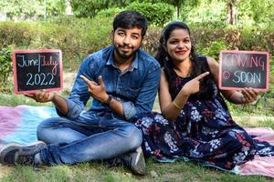 casal indiano posando para ensaio de maternidade. o casal está posando em um gramado com grama verde e a mulher está vacilando sua barriga no jardim lodhi em nova delhi, índia foto