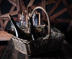 garrafa de champanhe com cesta de natal, guirlandas de ouro sobre fundo de madeira marrom escuro, conceito de celebração de ano novo foto
