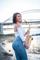 mulher tocando saxofone ao pôr do sol. foto