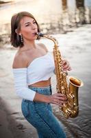 mulher tocando saxofone ao pôr do sol foto