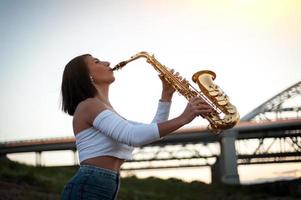 mulher tocando saxofone ao pôr do sol foto