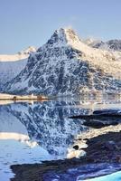 impulsionado por bo com montanhas refletindo na água. nas ilhas lofoten, noruega no inverno. foto