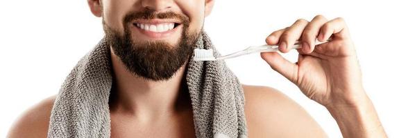 homem bonito com lindo sorriso segurando a escova de dentes no fundo branco