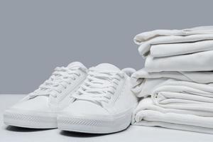 pilha de roupas brancas e tênis estilosos foto