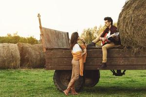 jovem casal na aldeia. cara está tocando violão para a namorada dela. foto