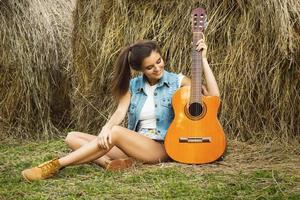 mulher jovem e feliz tocando violão na aldeia foto