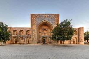 madari khan madrassah ostenta o pátio perfeitamente decorado com rendilhados de azulejos azuis nas paredes em bukhara, uzbequistão. foto