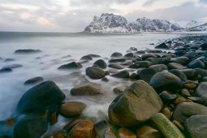 ondas fluindo sobre a praia de utakleiv, ilhas lofoten, noruega no inverno. foto