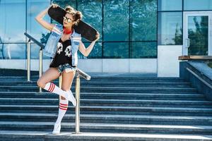 menina elegante com um skate na rua foto