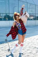 menina elegante com um skate na rua foto