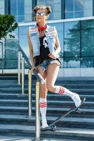 menina elegante com um skate na rua foto