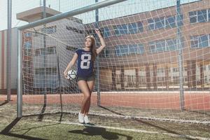 linda garota com bola no campo de futebol foto