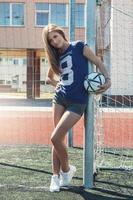 linda garota com bola no campo de futebol foto