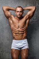 homem sexy e musculoso posando contra a parede de concreto foto