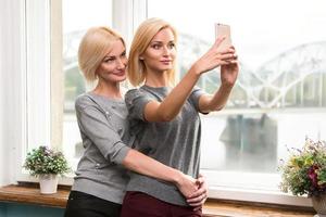 mãe e filha tirando uma selfie em casa foto