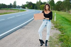 caroneiro na estrada está segurando uma placa de papelão em branco foto