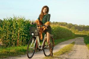 a mulher está pedalando pela estrada secundária no milharal foto