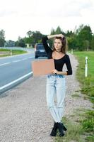 caroneiro na estrada está segurando uma placa de papelão em branco foto