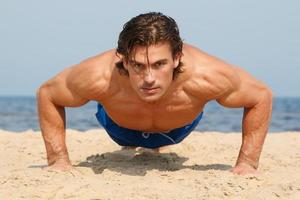 homem musculoso durante seu treino na praia foto