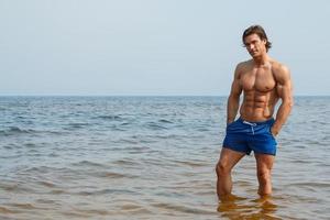 homem musculoso durante seu treino na praia foto
