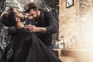 cabeleireiro durante o trabalho com um cliente cara na barbearia foto