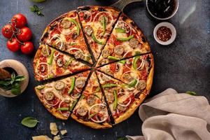 pizza de salsicha e legumes em fundo escuro foto