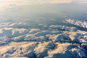 uma vista aérea das montanhas cobertas de neve dos fiordes da noruega no inverno. foto