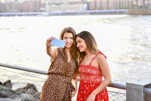 duas garotas interagindo com um celular e tirando selfies bobas na cidade de nova york foto