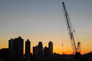 construção contra um fundo de uma silhueta da cidade de nova york ao pôr do sol. foto