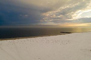 vista aérea de uma praia de coney island coberta de neve durante o inverno ao pôr do sol em brooklyn, nova york foto