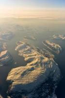 uma vista aérea das montanhas cobertas de neve dos fiordes da noruega no inverno. foto