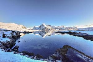 impulsionado por bo com montanhas refletindo na água. nas ilhas lofoten, noruega no inverno. foto