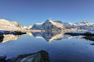 impulsionado por bo com montanhas refletindo na água. nas ilhas lofoten, noruega no inverno. foto