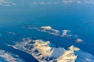 uma vista aérea das montanhas cobertas de neve dos fiordes da noruega no inverno. foto