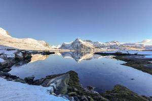 impulsionado por bo com montanhas refletindo na água. nas ilhas lofoten, noruega no inverno. foto